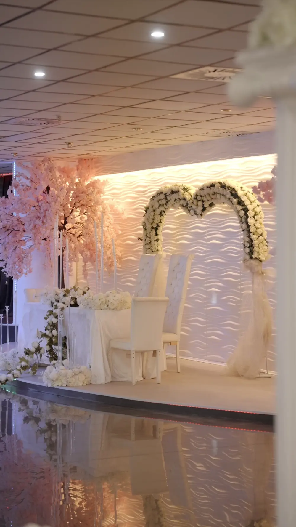 Ein festlich dekorierter Hochzeitstisch mit weißen Blumen und rosa Blütenbäumen